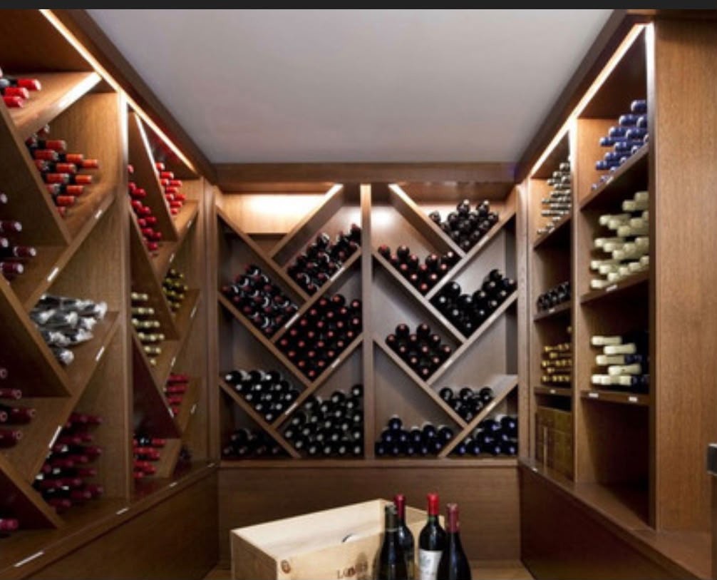 Cave à vin de prestige en bois foncé avec casiers en losange remplis de bouteilles et éclairage indirect