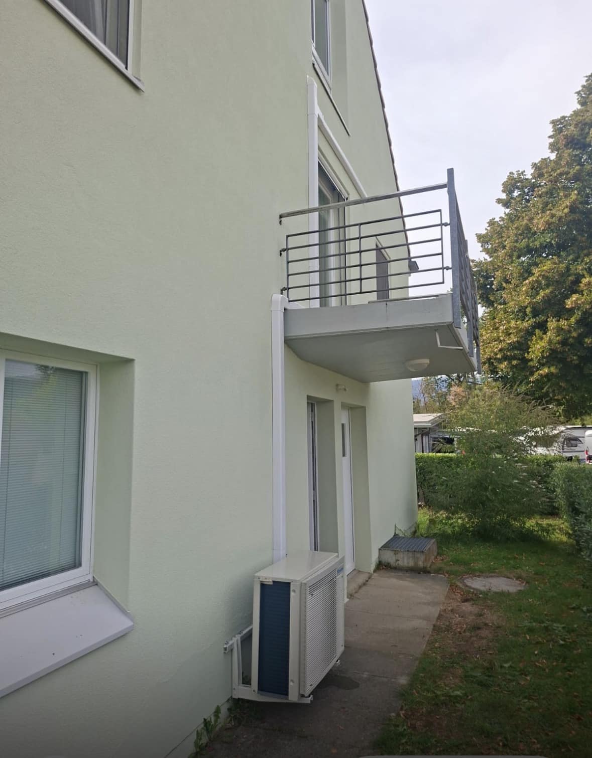 Unité extérieure de climatisation Daikin posée le long de la façade claire d'une villa