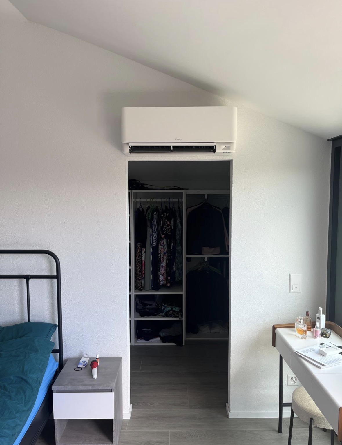 Unité murale Daikin blanche installée au-dessus de l'entrée du dressing d'une chambre parentale