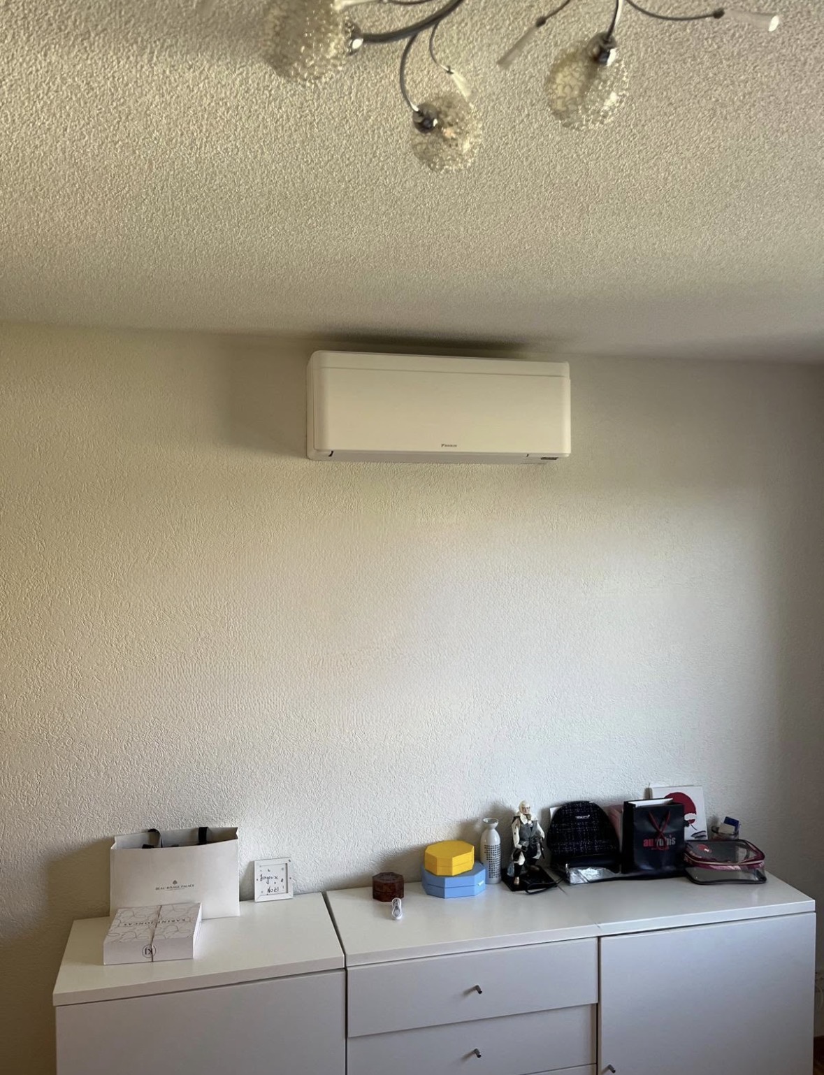 Split mural Daikin blanc posé en hauteur au-dessus d'une commode
