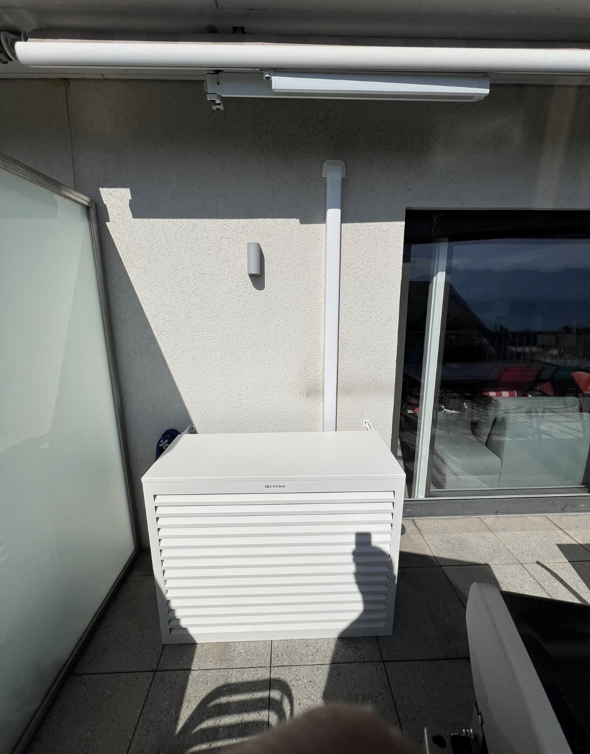 Cache Decoclim blanc à lames horizontales couvrant l'unité extérieure sur une terrasse d'attique