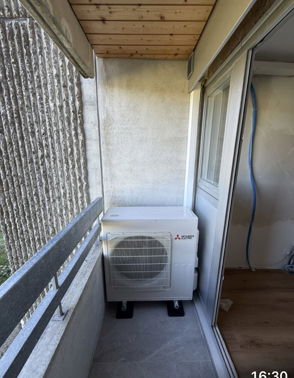 Vue d'ensemble du balcon avec l'unité extérieure Mitsubishi Electric et l'appartement en travaux