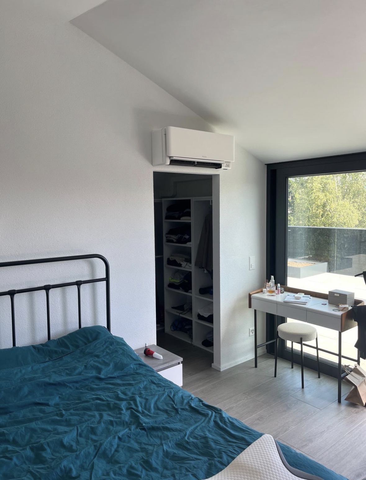 Vue d'ensemble de la chambre parentale avec le climatiseur mural Daikin et la baie vitrée
