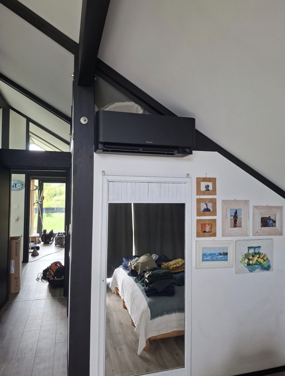 Split mural Daikin noir installé sous un rampant dans une chambre