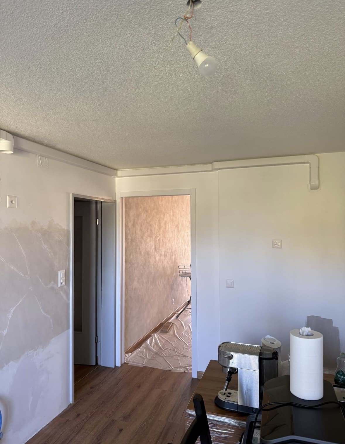 Goulotte blanche discrète longeant le plafond d'une pièce en rénovation pour le passage des liaisons frigorifiques