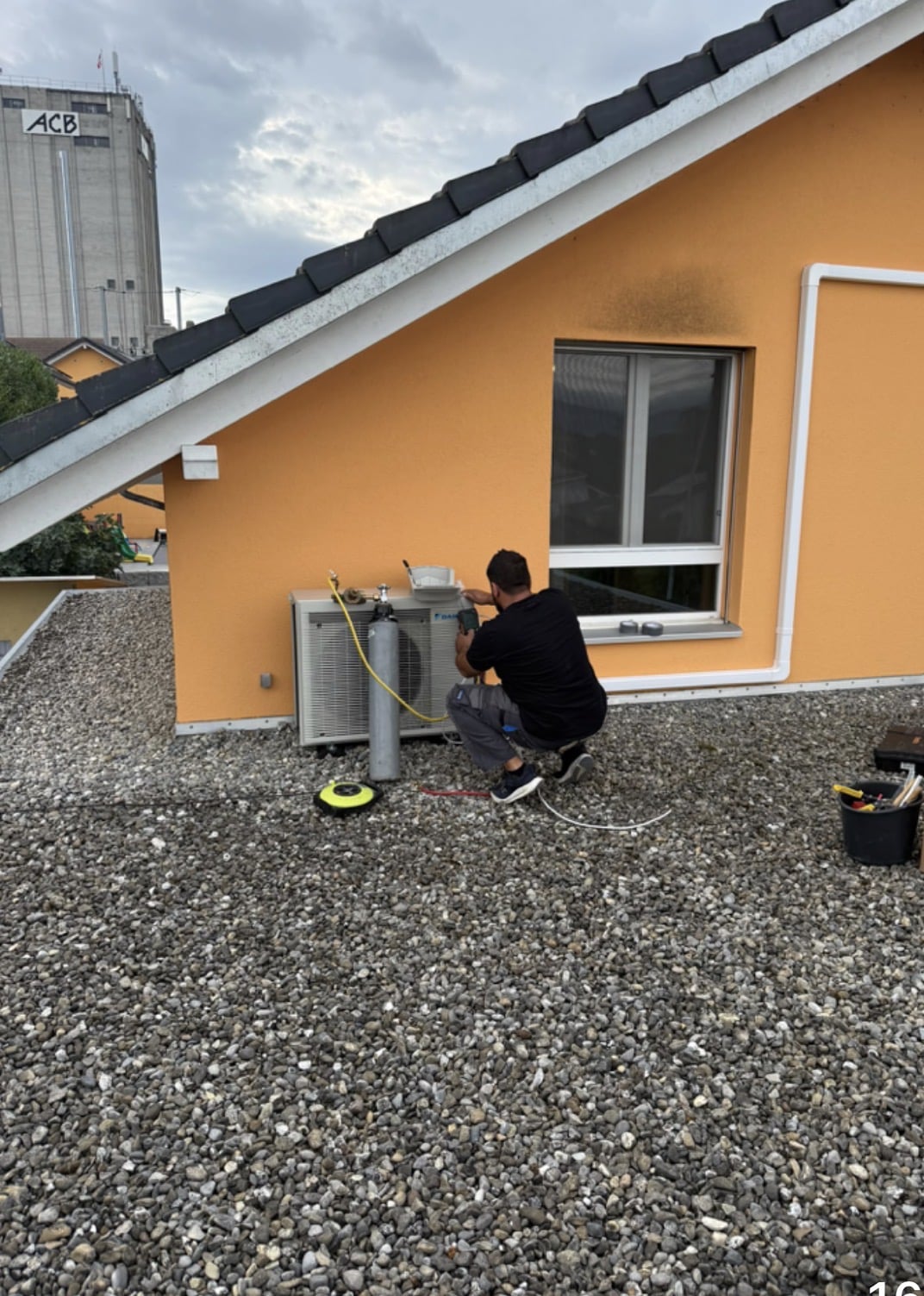 Technicien Electro-Climat raccordant l'unité extérieure Daikin le long de la façade orange de la villa