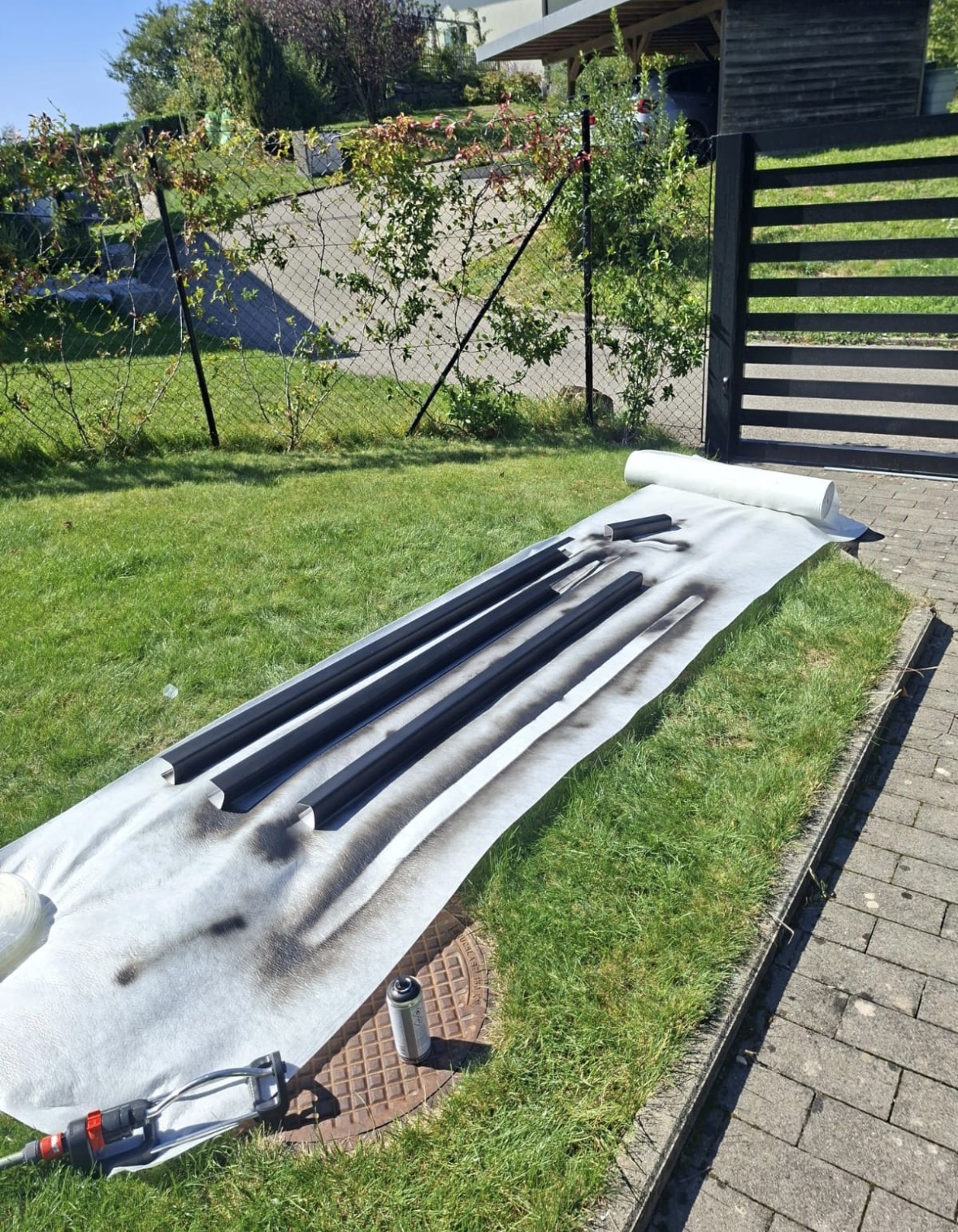 Goulottes mises en peinture noire sur une bâche de protection dans le jardin