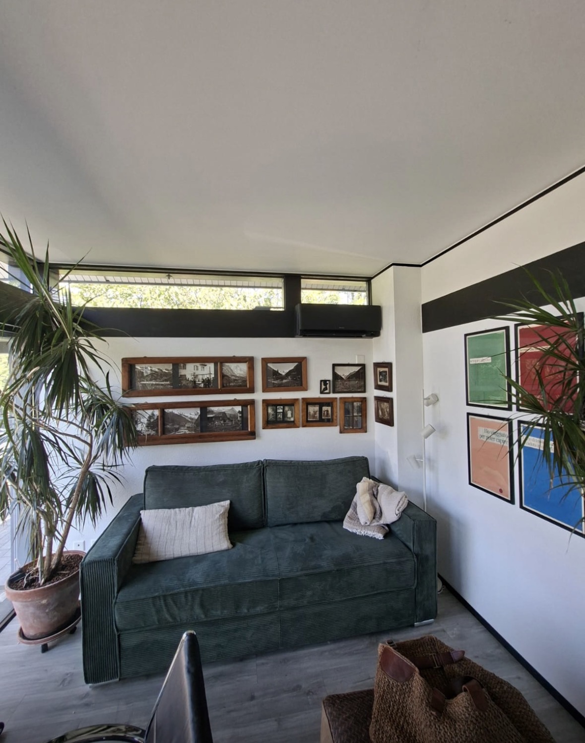 Salon avec unité murale noire placée sous un bandeau vitré horizontal
