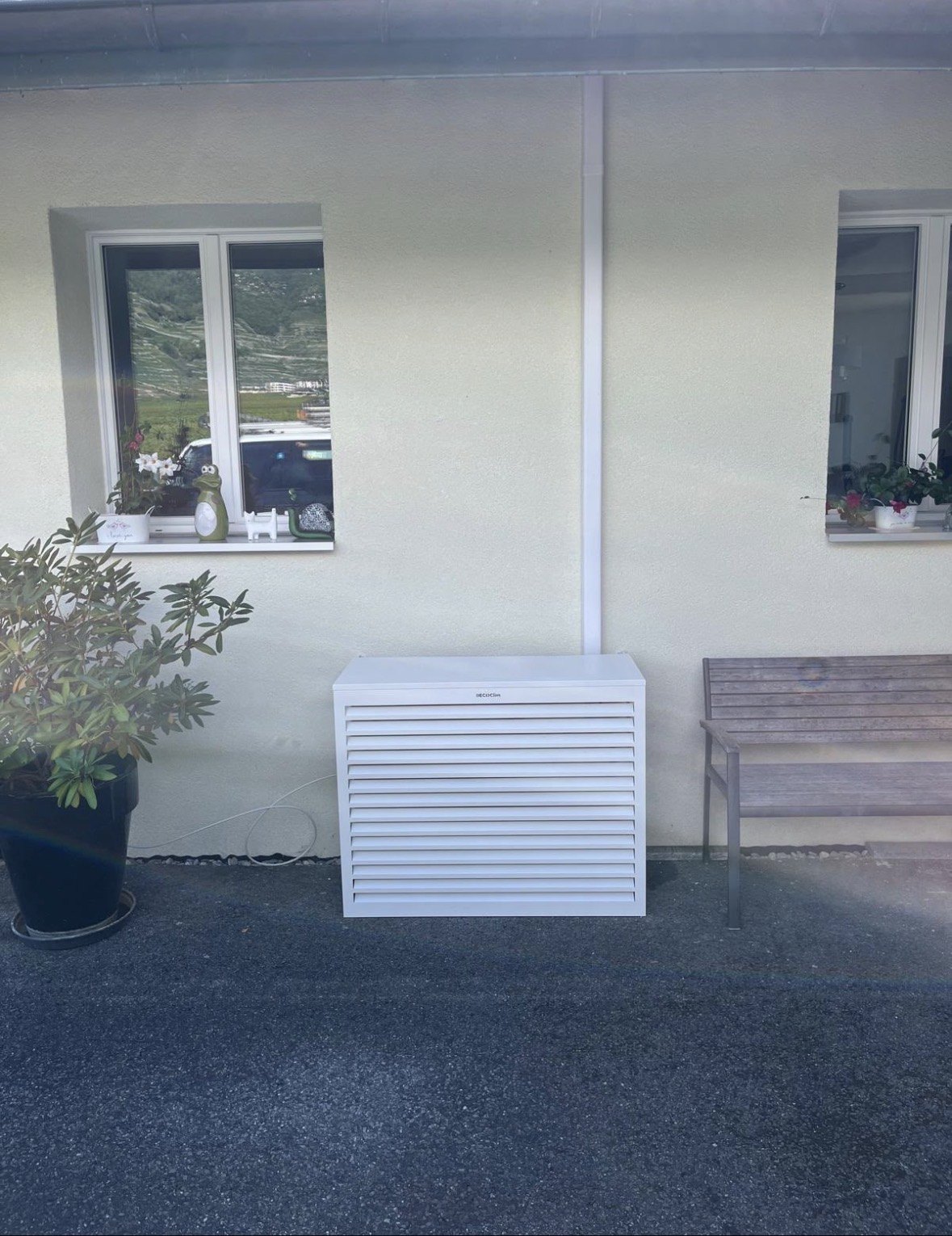 Groupe extérieur de climatisation habillé d'un cache blanc Decoclim contre la façade d'une villa à Grimisuat