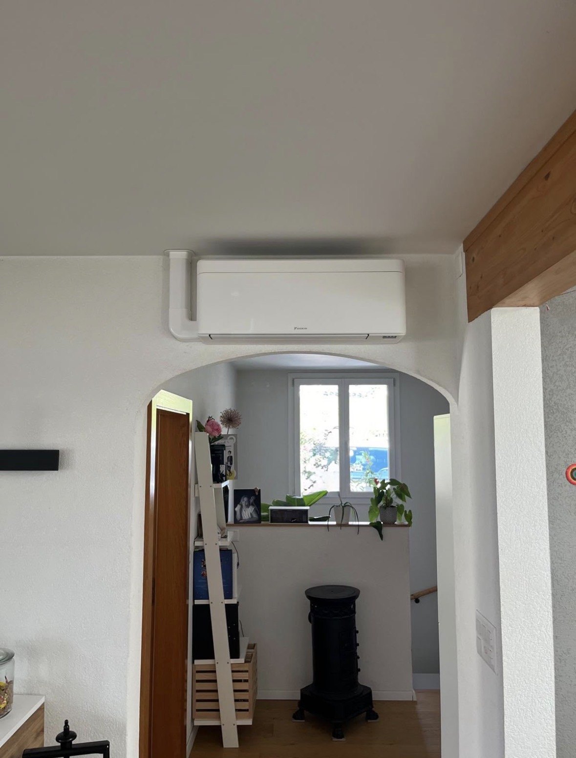 Unité intérieure murale Daikin blanche installée au-dessus d'une arche, dans le séjour d'une villa