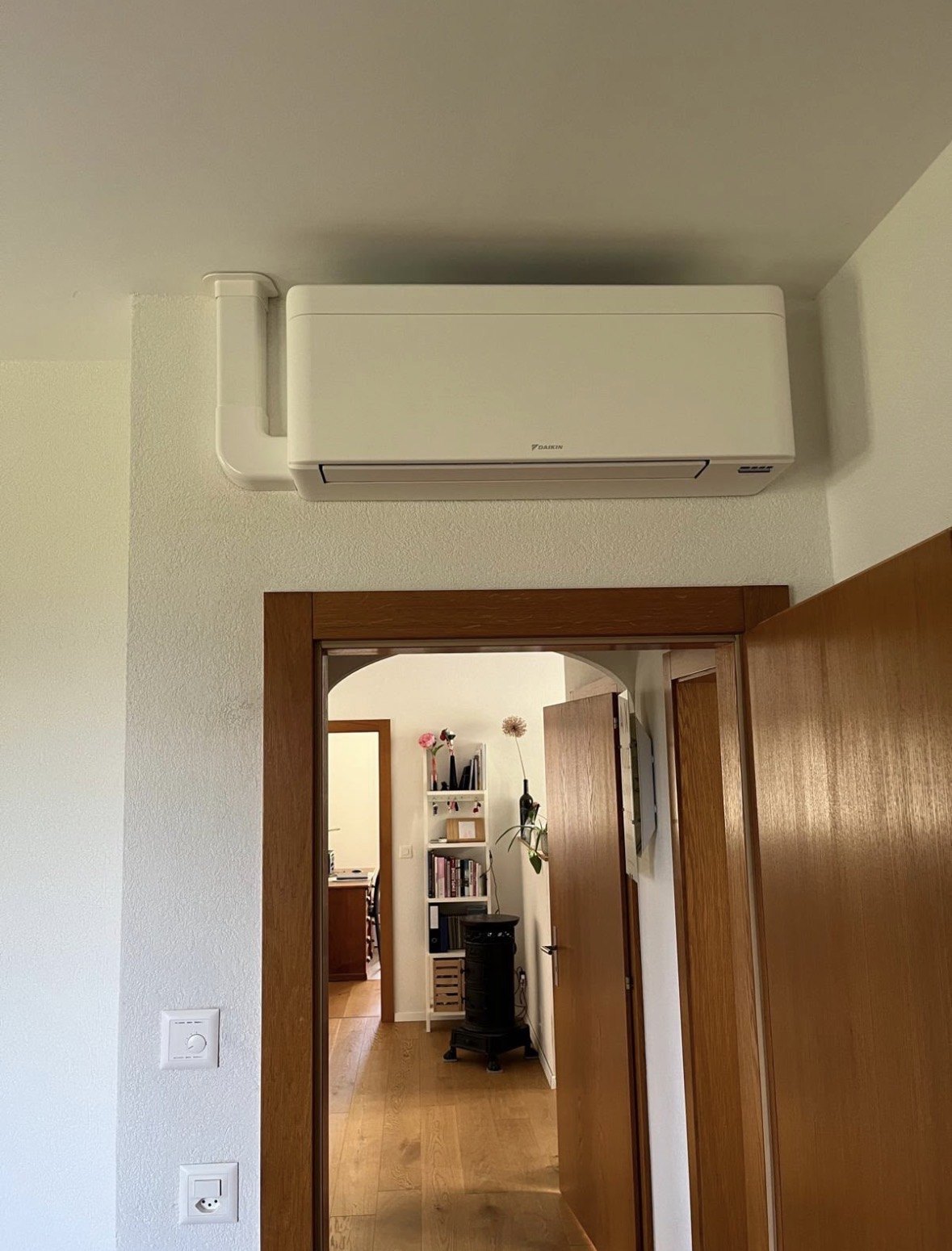 Unité intérieure murale Daikin installée au-dessus d'une porte, dans un couloir