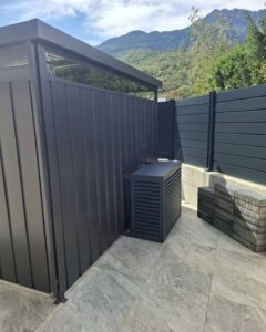 Unite exterieure de climatisation habillee d un cache Decoclim gris anthracite sur la terrasse d une villa