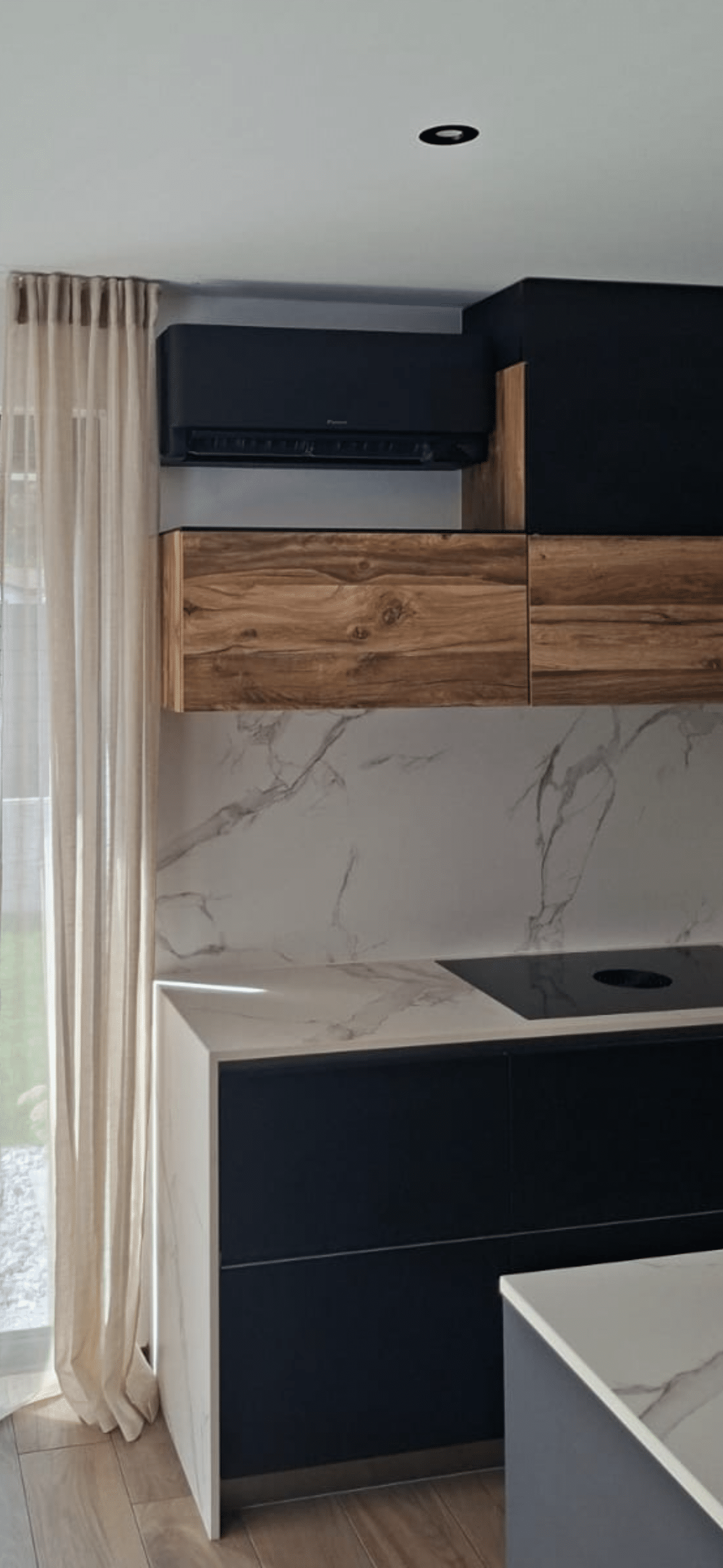Unité murale de climatisation Daikin Stylish noire installée au-dessus des meubles d'une cuisine