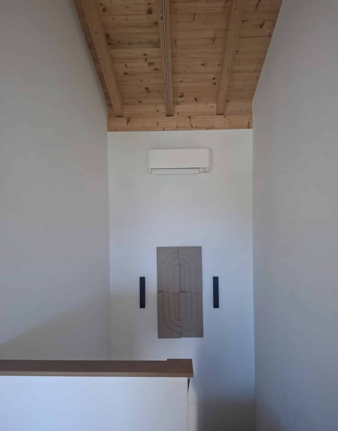 Unité murale Daikin Stylish blanche posée sous une charpente en bois apparente