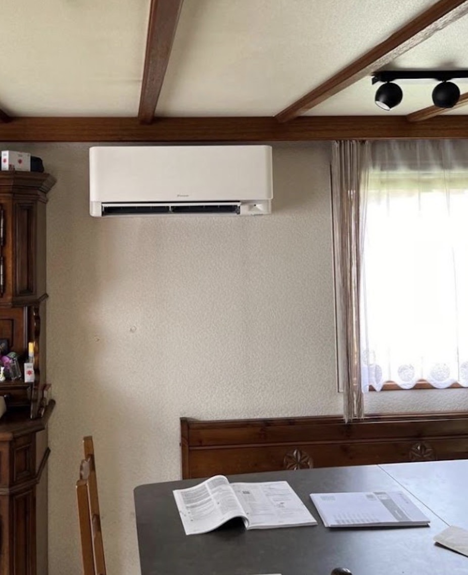 Unité murale Daikin installée dans le séjour d'un bungalow aux poutres apparentes