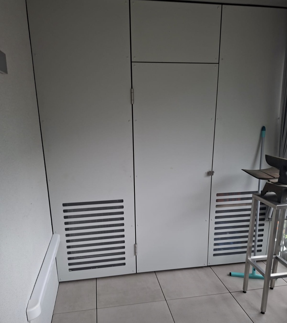 Armoire blanche équipée de deux grilles de ventilation discrètes dissimulant le groupe extérieur de climatisation