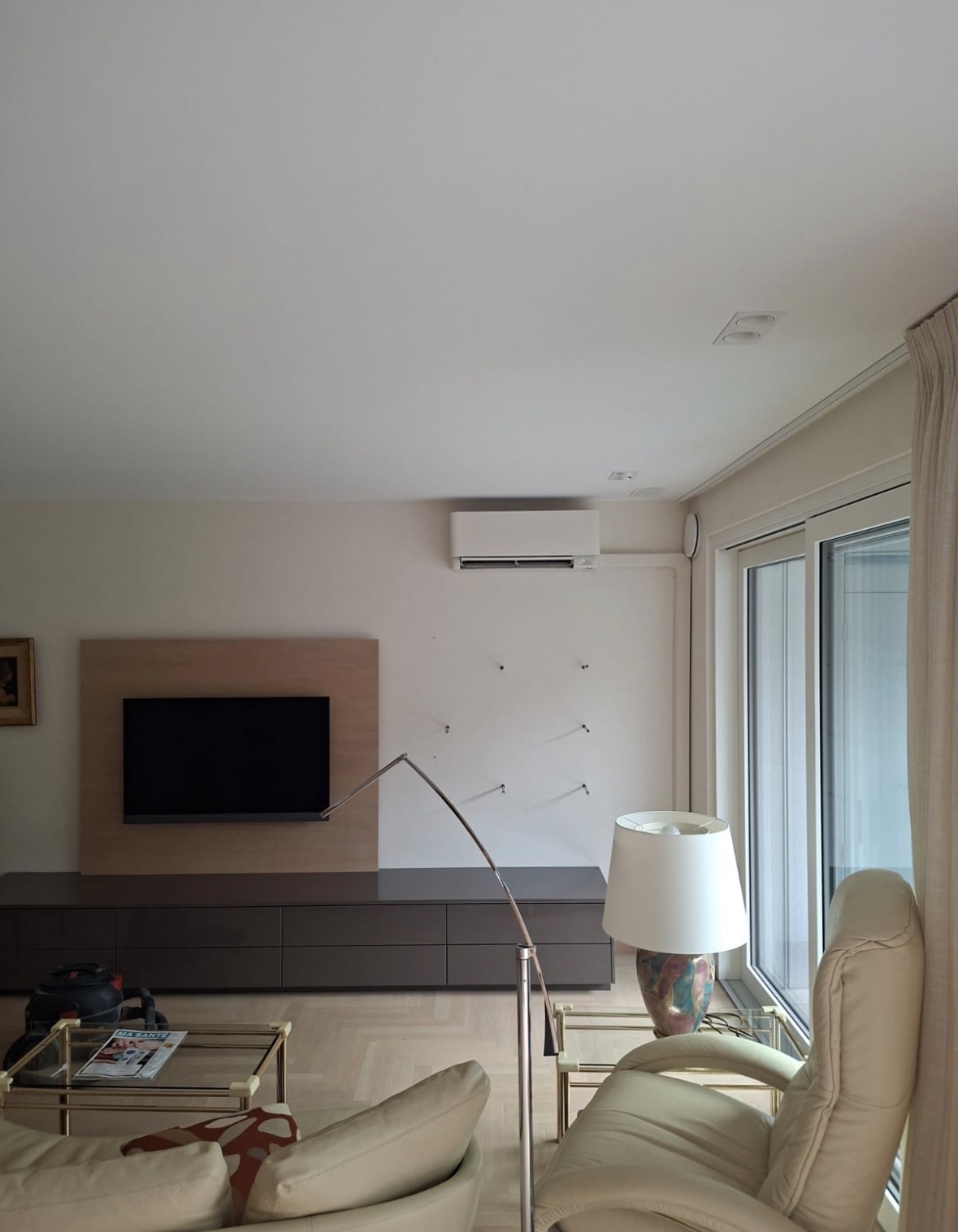 Unité murale de climatisation blanche installée en hauteur dans le séjour d'un appartement