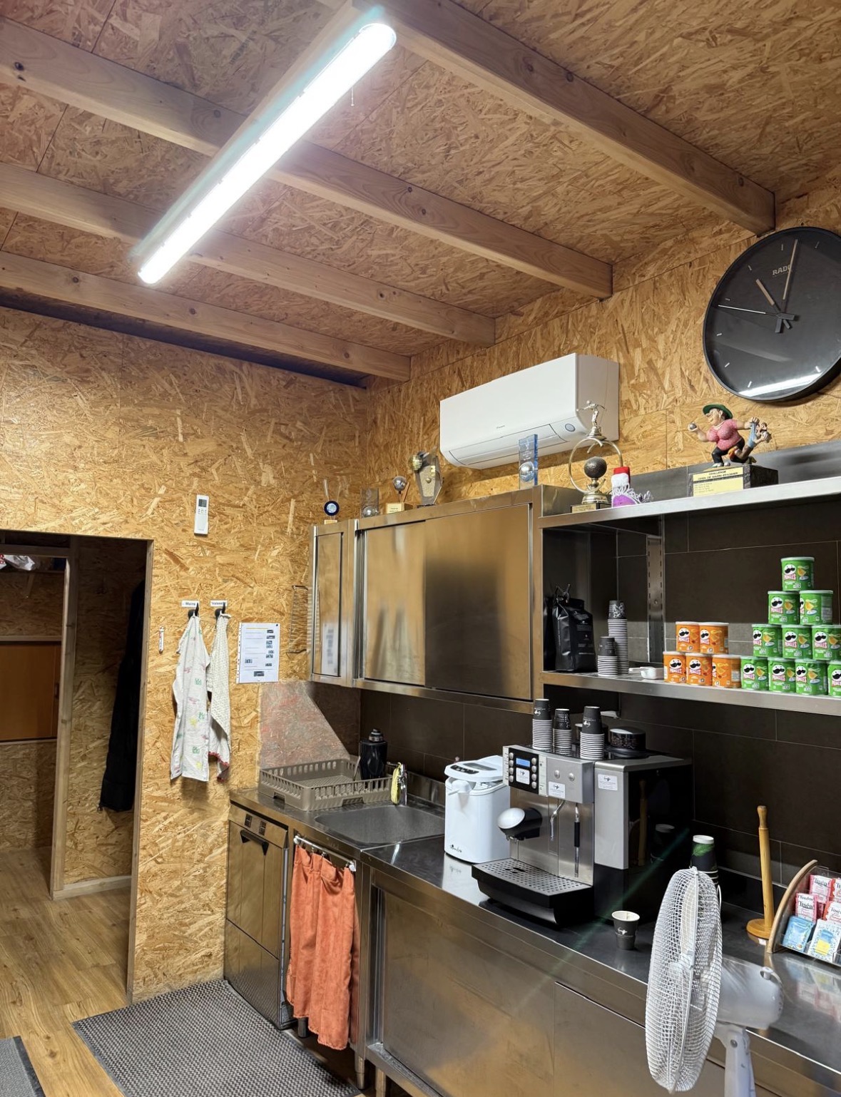 Unité murale Daikin posée en hauteur sur la paroi en bois d'une cuisine professionnelle de restaurant