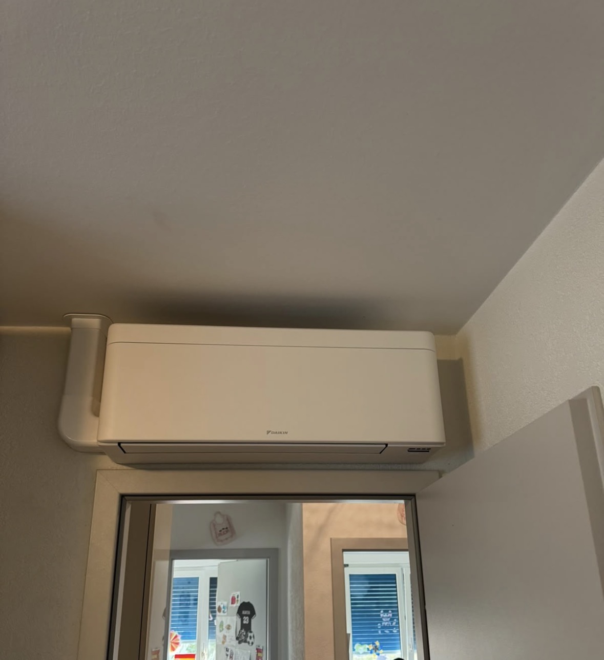 Unité murale Daikin blanche installée au-dessus d'une porte dans une chambre de la villa