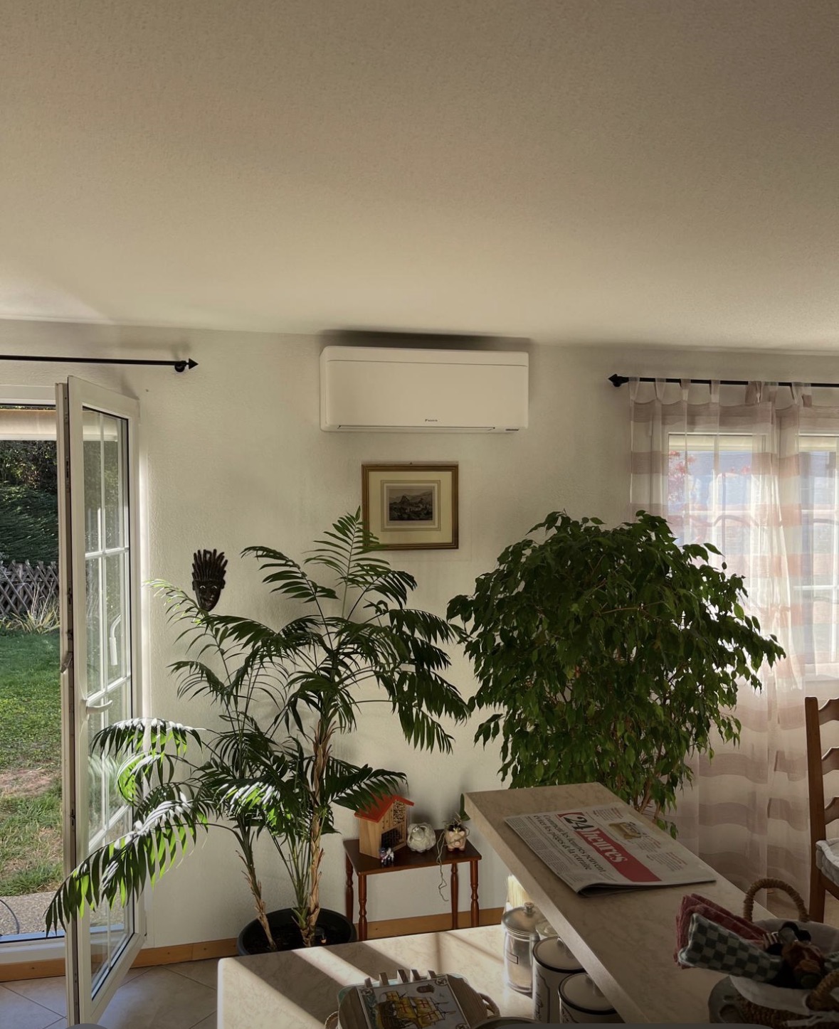 Unité murale de climatisation Daikin blanche installée en hauteur dans le séjour d'une villa