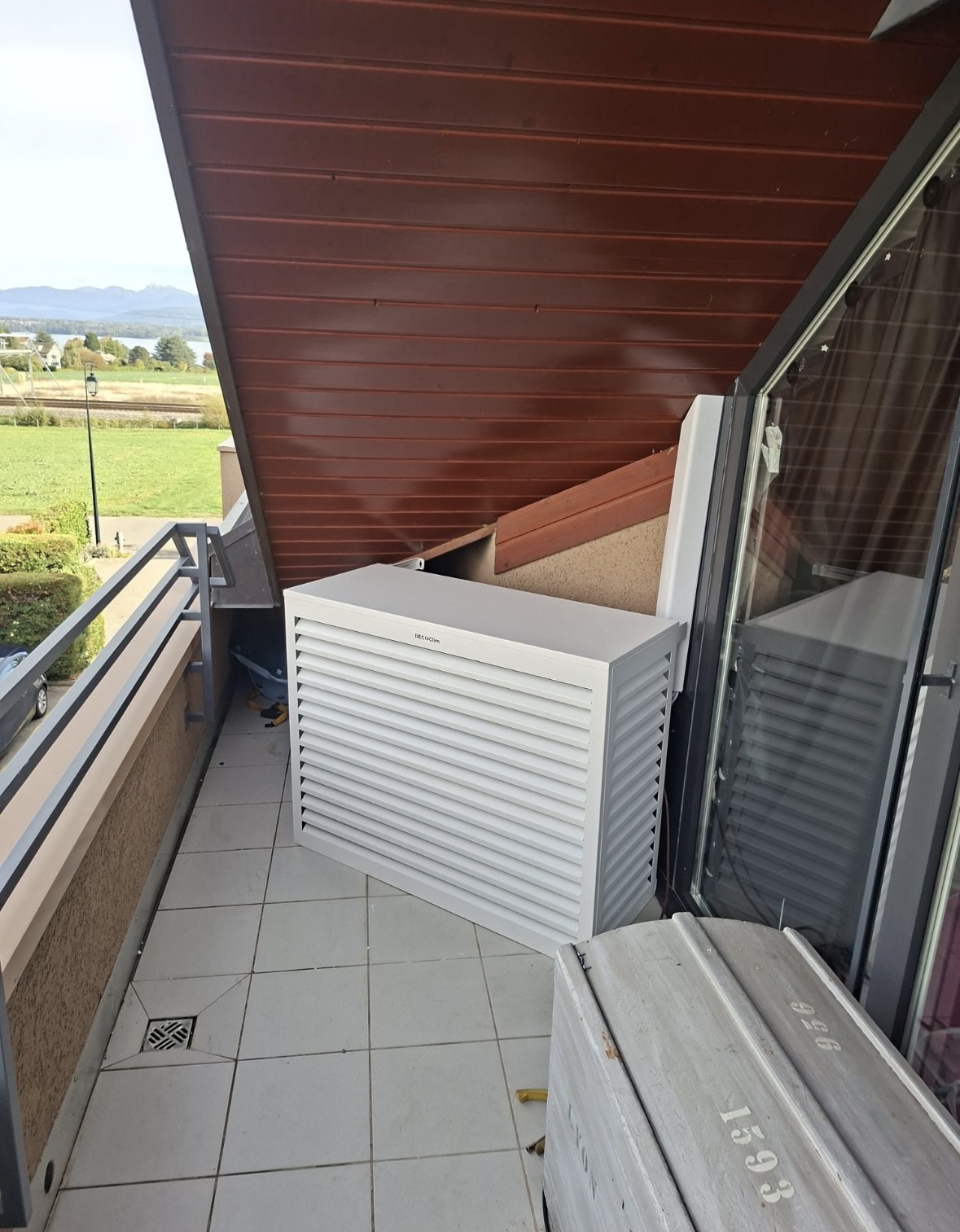 Unité extérieure de climatisation posée sur un balcon et habillée d'un cache technique blanc Decoclim