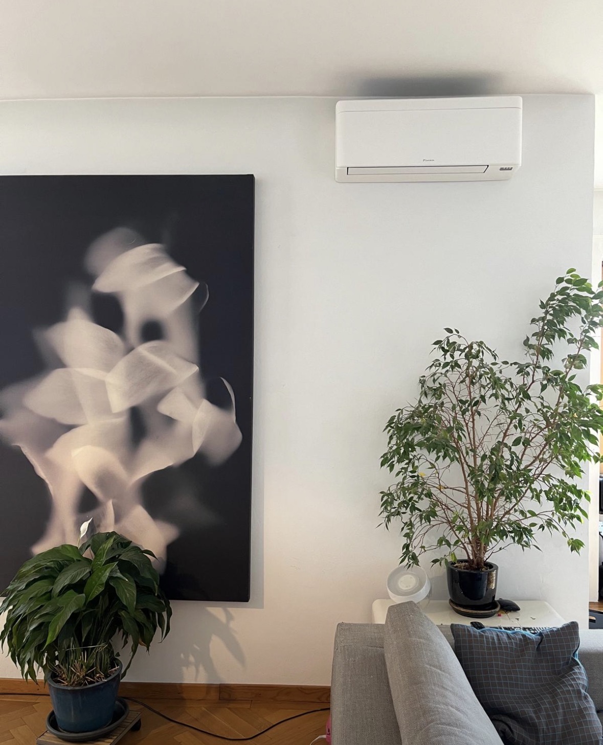 Unité intérieure murale Daikin Stylish blanche posée en partie haute d'un mur clair, au-dessus d'un canapé