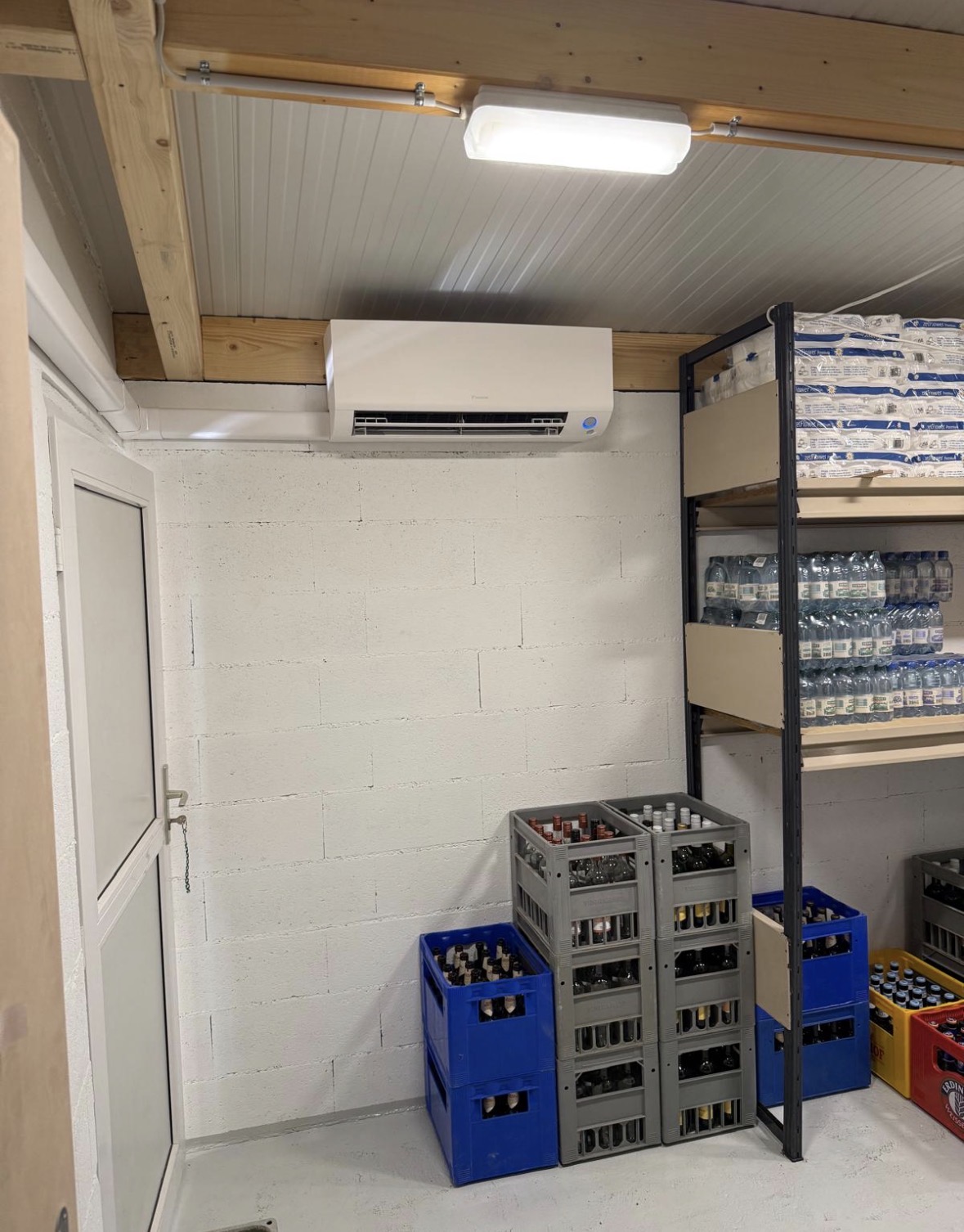 Split mural Daikin installé dans l'économat du restaurant, au-dessus des casiers de boissons et des rayonnages
