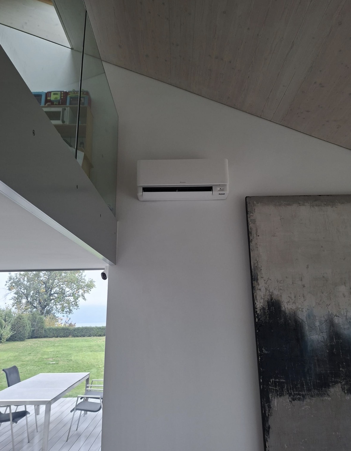 Unité murale Daikin Stylish installée en hauteur dans un séjour avec plafond en bois et vue sur le lac