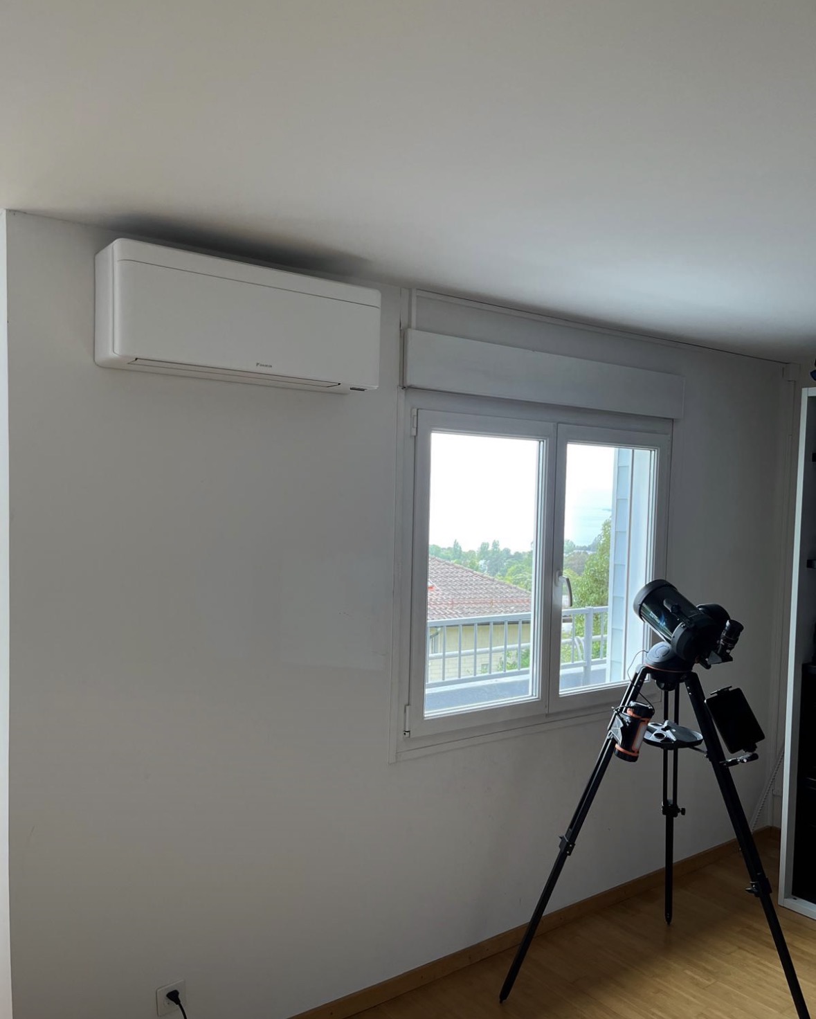 Split mural Daikin Stylish installé en hauteur sur un mur clair, à côté d'une fenêtre