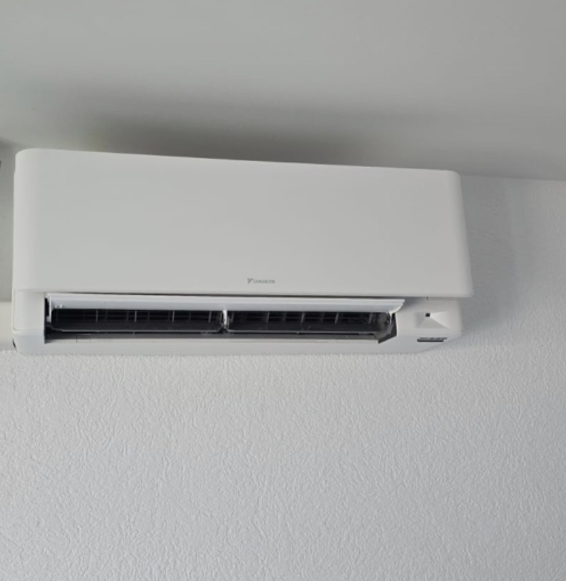 Gros plan sur une unité intérieure Daikin Stylish murale blanche, volet ouvert, installée sous le plafond