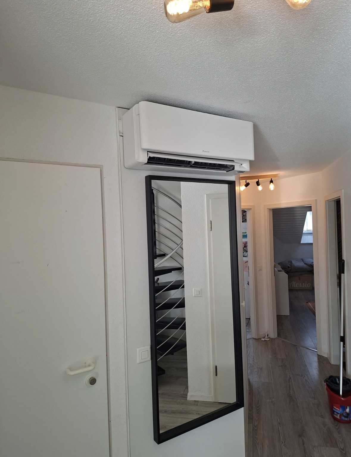 Split mural Daikin installé au-dessus d'une porte dans un couloir de logement