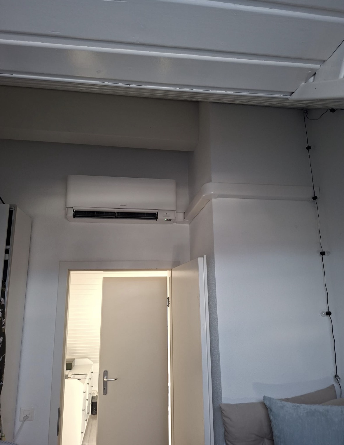 Unité intérieure Daikin et goulotte blanche suivant la retombée du plafond d'une chambre
