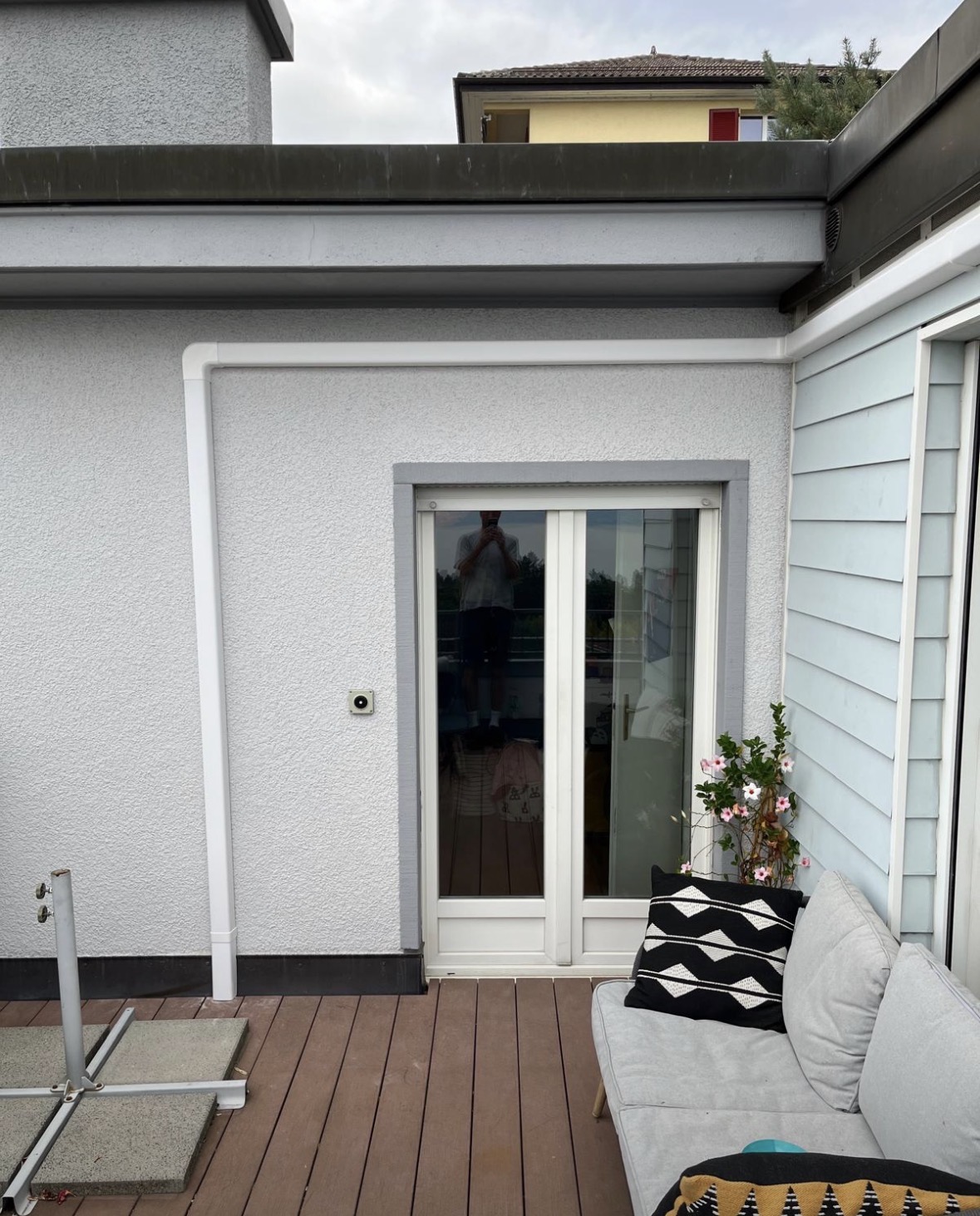 Goulotte blanche discrète cheminant sur la façade crépie au-dessus d'une porte-fenêtre