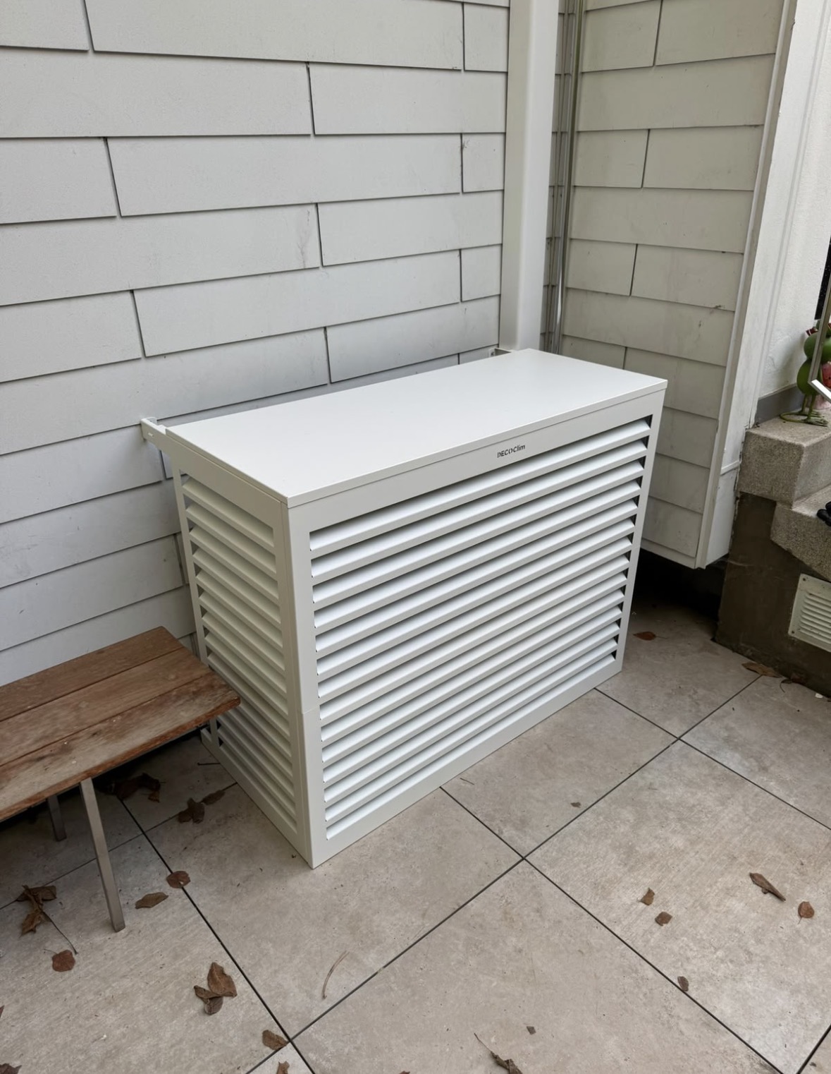 Cache Decoclim blanc à lamelles habillant l'unité extérieure de climatisation sur la terrasse