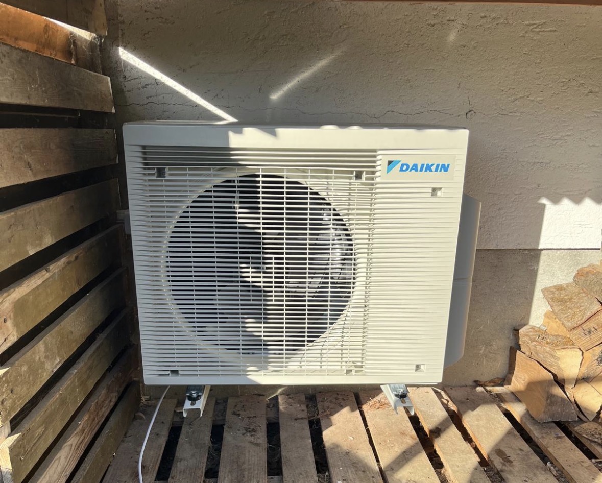Unité extérieure Daikin fixée au mur sous un couvert à bois