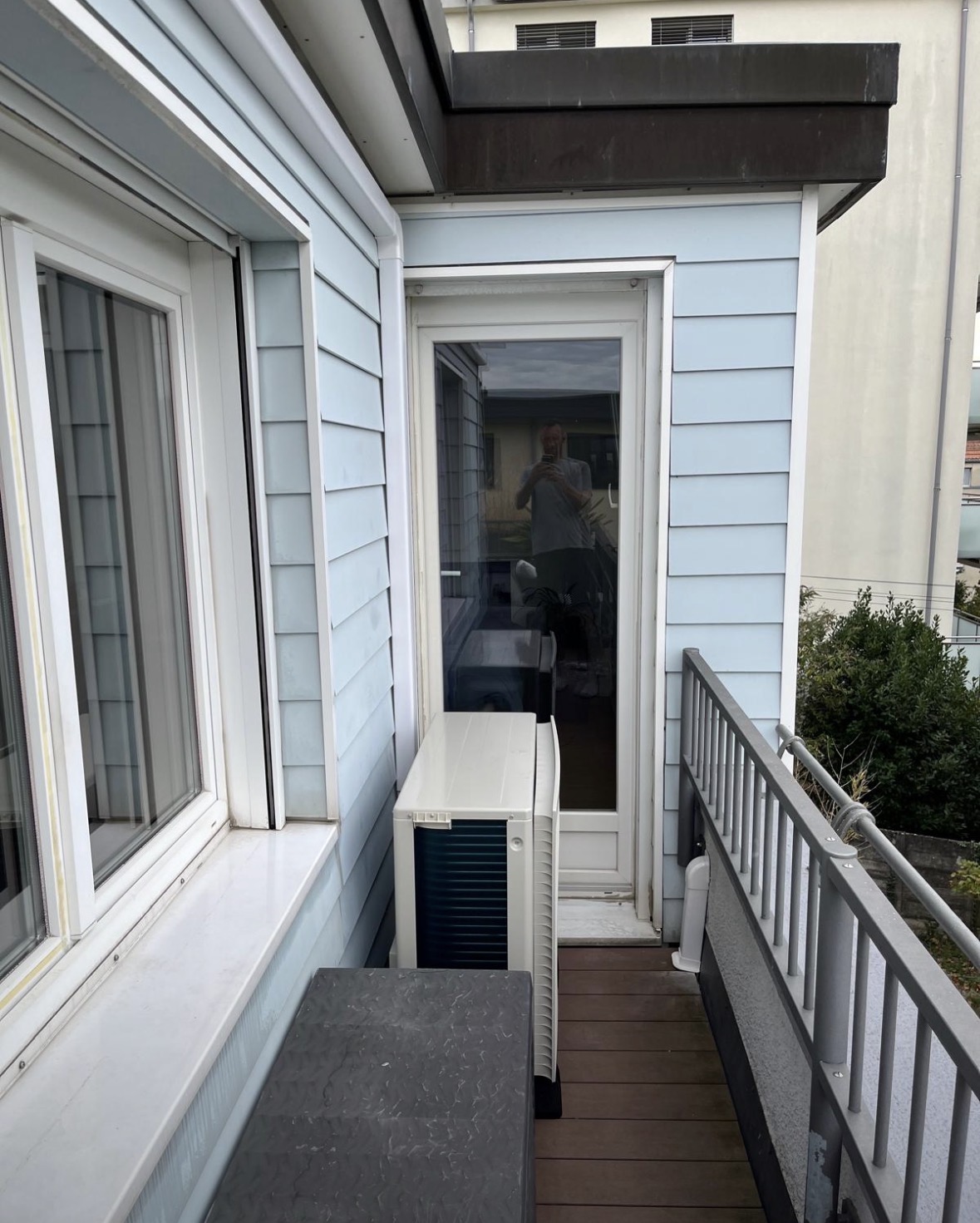Unité extérieure Daikin installée le long d'un balcon étroit contre une façade en bois clair