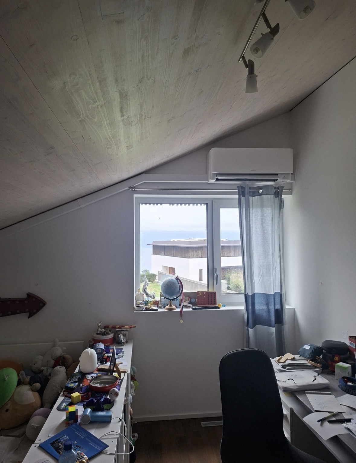 Unité Daikin Stylish posée au-dessus d'une fenêtre dans une chambre mansardée avec vue sur le lac