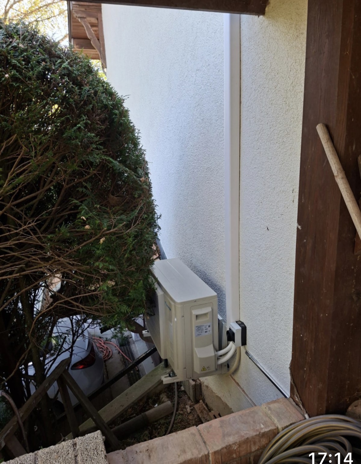 Seconde unité extérieure Daikin fixée en applique sur le mur, masquée par une haie